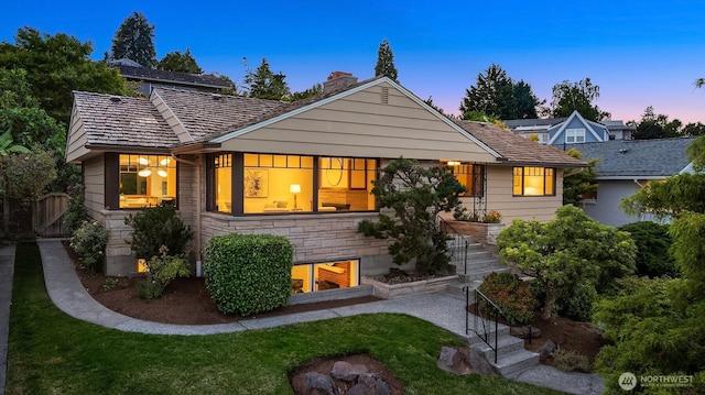 5244 Pullman Ave NE, Seattle, WA 98105 - back of property at dusk with a chimney, a yard, stone siding, and stairs