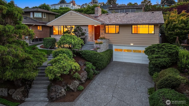 5244 Pullman Ave NE, Seattle, WA 98105 - view of front facade featuring an attached garage, stairway, driveway, and a chimney