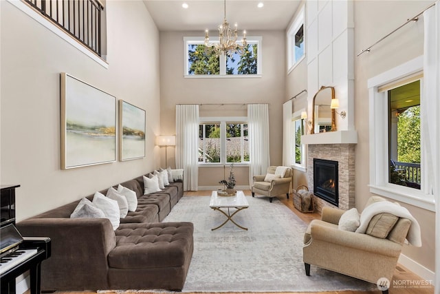 230 155th Pl SE, Bothell, WA 98012 - living room featuring a high ceiling, a chandelier, a glass covered fireplace, wood finished floors, and recessed lighting