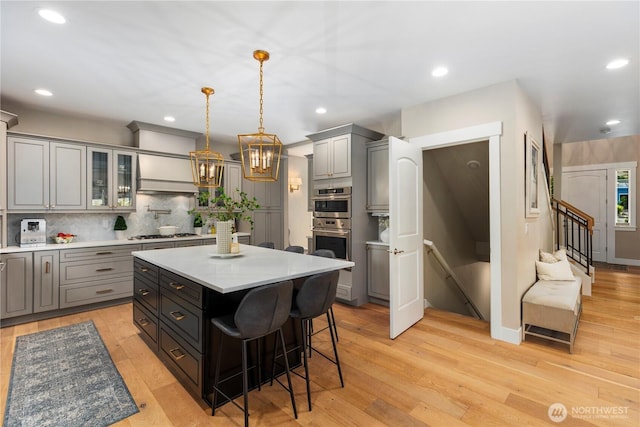 230 155th Pl SE, Bothell, WA 98012 - kitchen with gray cabinetry, light countertops, glass insert cabinets, a kitchen breakfast bar, and a center island