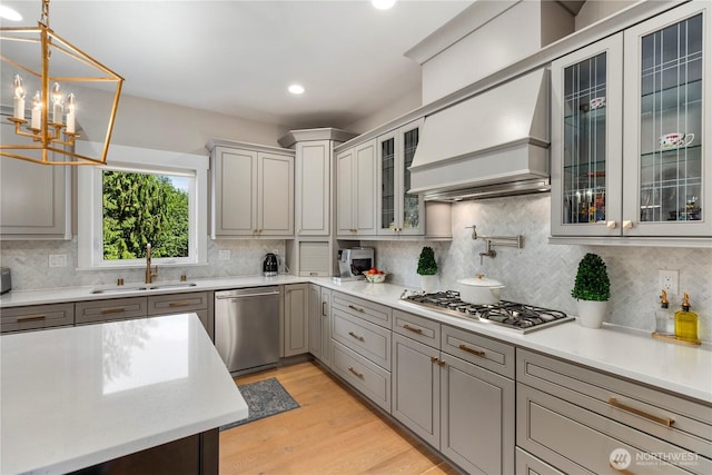 230 155th Pl SE, Bothell, WA 98012 - kitchen with appliances with stainless steel finishes, custom range hood, backsplash, hanging light fixtures, and light wood-type flooring