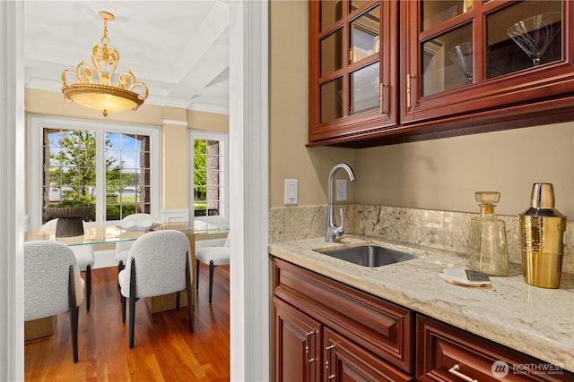 2530 39th Ave E, Seattle, WA 98112 - kitchen featuring crown molding, light stone countertops, reddish brown cabinets, wood finished floors, and glass insert cabinets