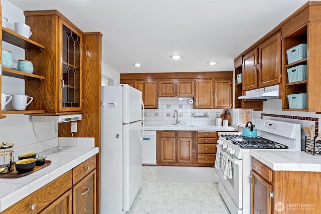 7147 29th Ave SW, Seattle, WA 98126 - kitchen with open shelves, white appliances, under cabinet range hood, tile countertops, and brown cabinetry