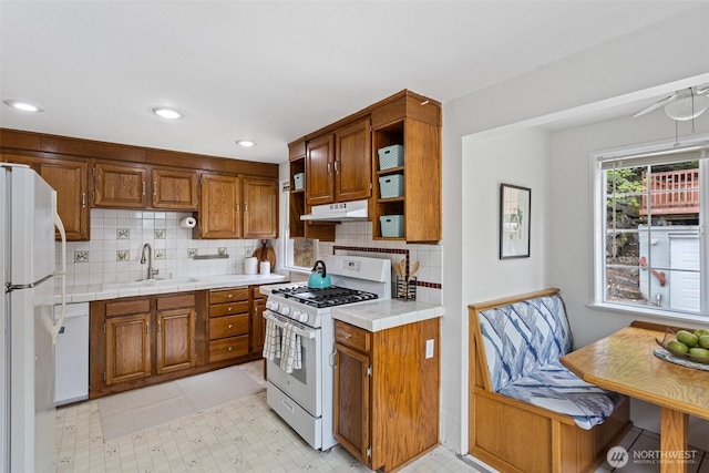 7147 29th Ave SW, Seattle, WA 98126 - kitchen featuring white appliances, open shelves, brown cabinets, under cabinet range hood, and backsplash