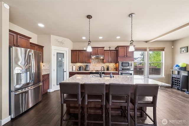 17116 138th Ave E, Puyallup, WA 98374 - kitchen with appliances with stainless steel finishes, under cabinet range hood, dark wood-style floors, decorative backsplash, and recessed lighting