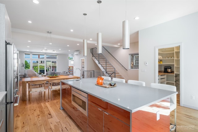 6012 Palatine Ave N, Seattle, WA 98103 - kitchen featuring appliances with stainless steel finishes, open floor plan, light wood-style floors, recessed lighting, and a kitchen bar