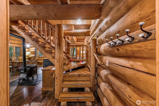 7010 Rainier Way, Deming, WA 98244 - stairway with log walls, wood-type flooring, a wood stove, and beamed ceiling