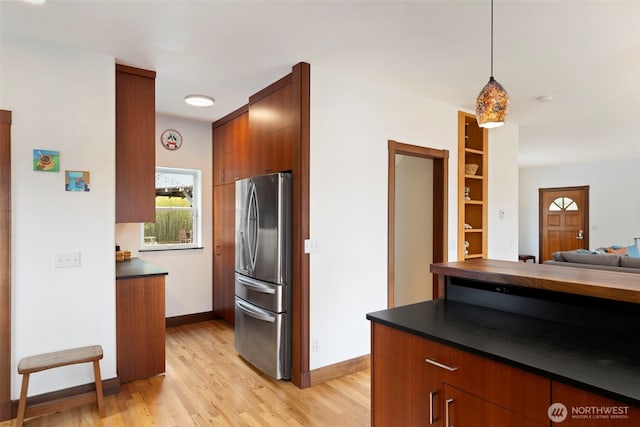 788 P St, Port Townsend, WA 98368 - kitchen featuring stainless steel fridge, dark countertops, light wood finished floors, modern cabinets, and decorative light fixtures