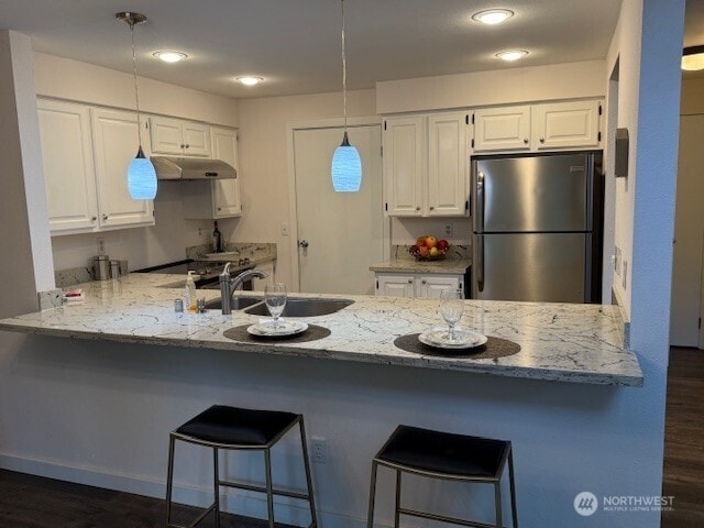 1555 Union Ave NE Unit 56, Renton, WA 98059 - kitchen featuring freestanding refrigerator, a peninsula, white cabinets, light stone countertops, and pendant lighting