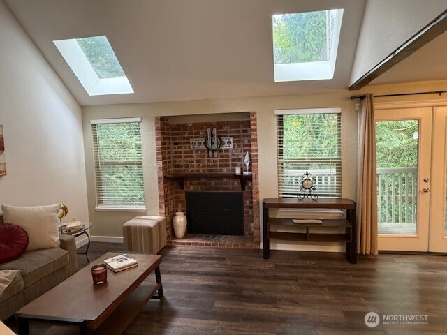 1555 Union Ave NE Unit 56, Renton, WA 98059 - living area featuring a skylight, vaulted ceiling, a brick fireplace, wood finished floors, and plenty of natural light