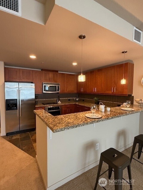 1515 Dock St Unit 210, Tacoma, WA 98402 - kitchen with stainless steel appliances, brown cabinetry, dark stone countertops, and recessed lighting