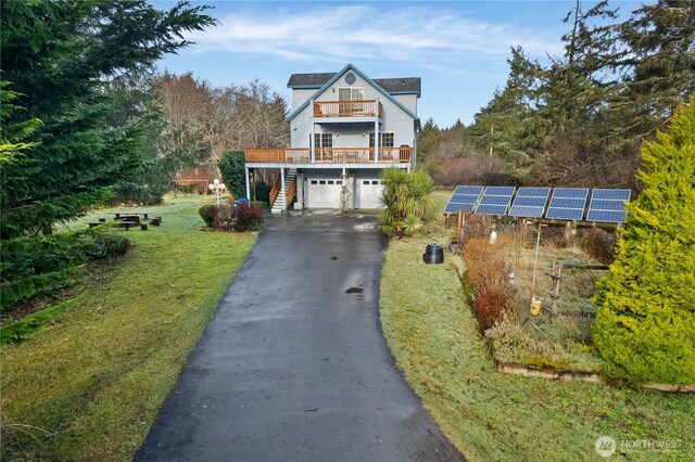 11 Condra Rd, Copalis Beach, WA 98535 - view of front of home featuring asphalt driveway, an attached garage, stairs, solar panels, and a front yard
