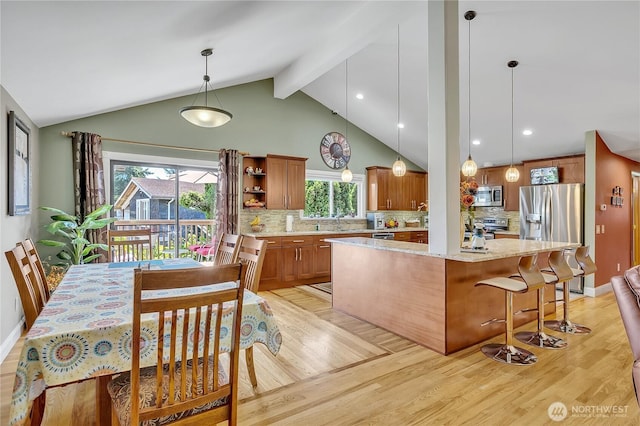 5103 S 302nd Pl, Auburn, WA 98001 - kitchen featuring appliances with stainless steel finishes, light wood-style floors, a center island, brown cabinets, and tasteful backsplash
