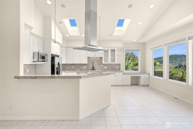 2011 Eldridge Ave, Bellingham, WA 98225 - kitchen featuring stainless steel appliances, a skylight, island range hood, white cabinetry, and tasteful backsplash