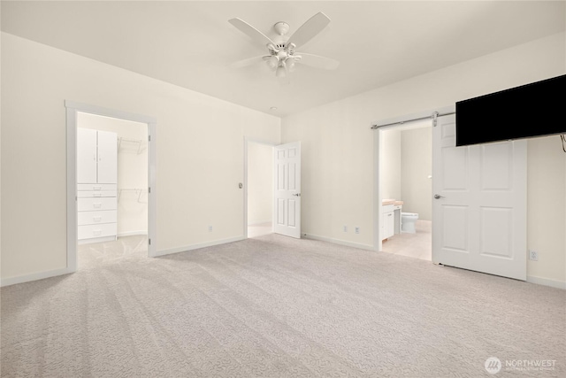 2011 Eldridge Ave, Bellingham, WA 98225 - unfurnished bedroom with a walk in closet, light carpet, connected bathroom, a barn door, and ceiling fan