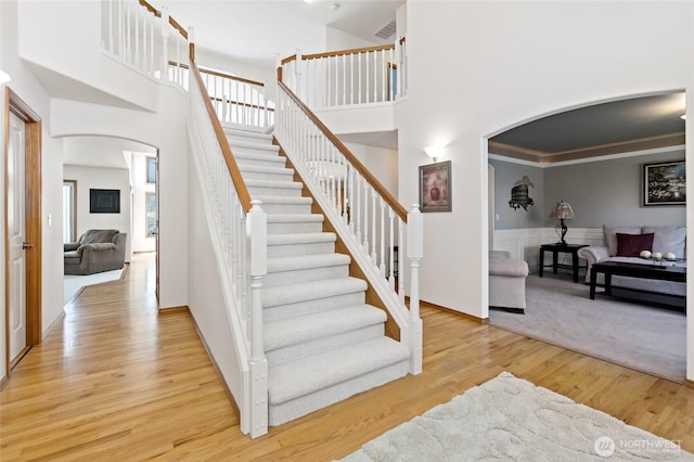 4024RD E Caldwell, Edgewood, WA 98372 - stairway with arched walkways, a towering ceiling, wood finished floors, and a wainscoted wall
