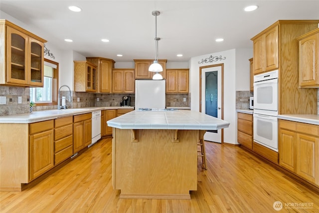 4024RD E Caldwell, Edgewood, WA 98372 - kitchen featuring white appliances, light wood-style flooring, a center island, a breakfast bar, and tasteful backsplash