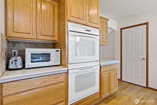 4024RD E Caldwell, Edgewood, WA 98372 - kitchen with white appliances, tile counters, decorative backsplash, and light wood-type flooring