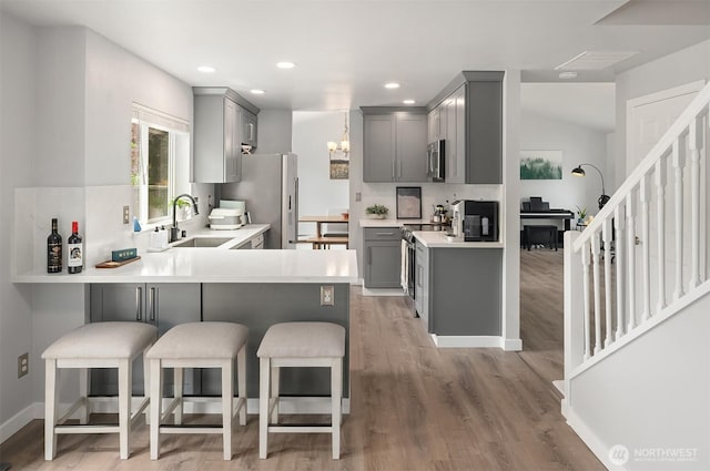 23619 SE 245th St, Maple Valley, WA 98038 - kitchen featuring gray cabinets, a peninsula, stainless steel appliances, a kitchen bar, and light countertops