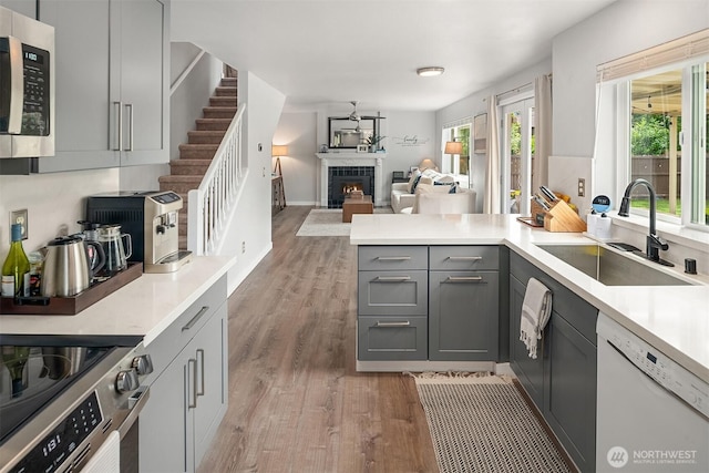 23619 SE 245th St, Maple Valley, WA 98038 - kitchen featuring stainless steel appliances, gray cabinets, light wood finished floors, a peninsula, and a warm lit fireplace