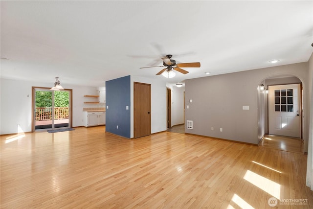 7511 Kittiwake Dr SE, Olympia, WA 98513 - unfurnished living room with arched walkways, ceiling fan, and light wood-style floors