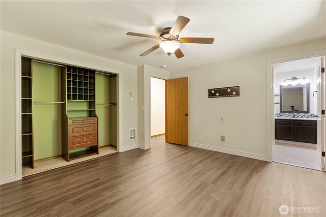 7511 Kittiwake Dr SE, Olympia, WA 98513 - unfurnished bedroom with wood finished floors, a closet, connected bathroom, and ceiling fan