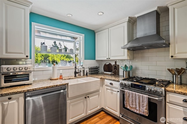 14618 SE 275th Pl, Kent, WA 98042 - kitchen featuring appliances with stainless steel finishes, wall chimney range hood, backsplash, light stone countertops, and recessed lighting