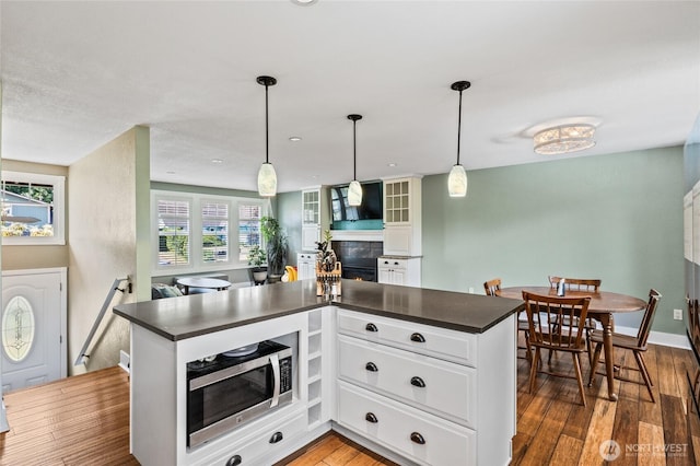 14618 SE 275th Pl, Kent, WA 98042 - kitchen with dark countertops, a fireplace, stainless steel microwave, and wood finished floors
