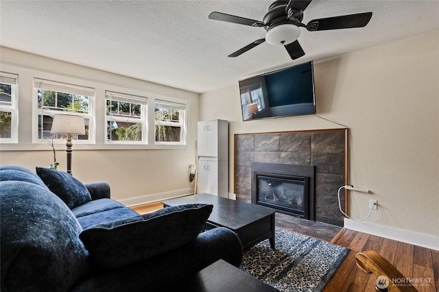 14618 SE 275th Pl, Kent, WA 98042 - living room featuring wood finished floors, a tiled fireplace, healthy amount of natural light, a ceiling fan, and a textured ceiling