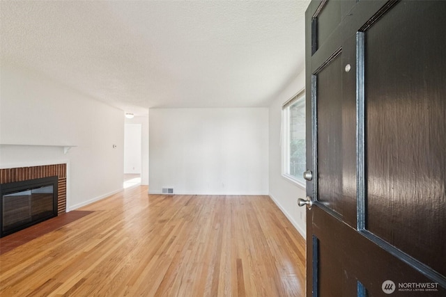14326 Meridian Ave N, Seattle, WA 98133 - unfurnished living room with light wood finished floors, a brick fireplace, and a textured ceiling