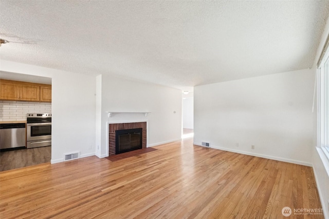 14326 Meridian Ave N, Seattle, WA 98133 - unfurnished living room featuring light wood-style flooring, a textured ceiling, and a fireplace