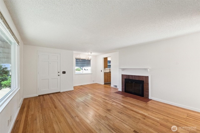 14326 Meridian Ave N, Seattle, WA 98133 - unfurnished living room with a chandelier, light wood-type flooring, a textured ceiling, and a fireplace