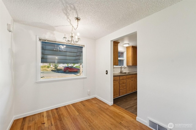 14326 Meridian Ave N, Seattle, WA 98133 - unfurnished dining area featuring a chandelier, wood finished floors, and a textured ceiling