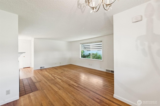 14326 Meridian Ave N, Seattle, WA 98133 - unfurnished living room with a chandelier, wood finished floors, and a textured ceiling