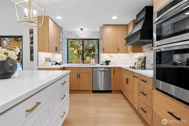 9320 Hoeder Ln, Bothell, WA 98011 - kitchen featuring stainless steel appliances, wall chimney exhaust hood, light wood-type flooring, decorative backsplash, and a chandelier