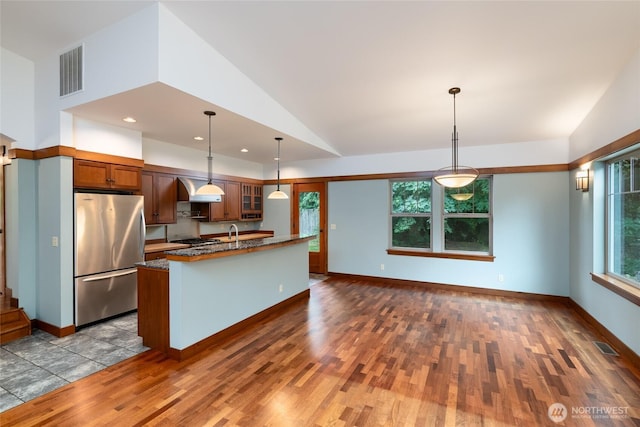 14450 Austin Pl, Anacortes, WA 98221 - kitchen featuring freestanding refrigerator, dark wood finished floors, glass insert cabinets, an island with sink, and hanging light fixtures
