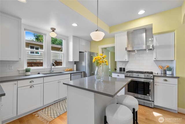 1531 NW 62nd St, Seattle, WA 98107 - kitchen with appliances with stainless steel finishes, wall chimney range hood, dark countertops, white cabinetry, and recessed lighting