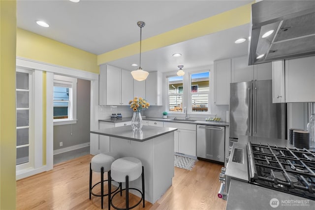 1531 NW 62nd St, Seattle, WA 98107 - kitchen featuring appliances with stainless steel finishes, backsplash, light wood-type flooring, island range hood, and recessed lighting