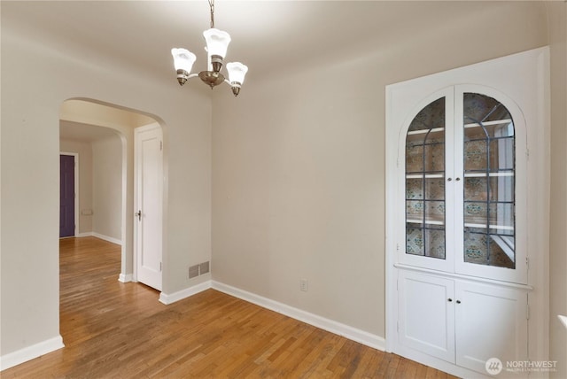 239 S 58th St, Tacoma, WA 98408 - unfurnished room with arched walkways, a chandelier, and light wood-style flooring