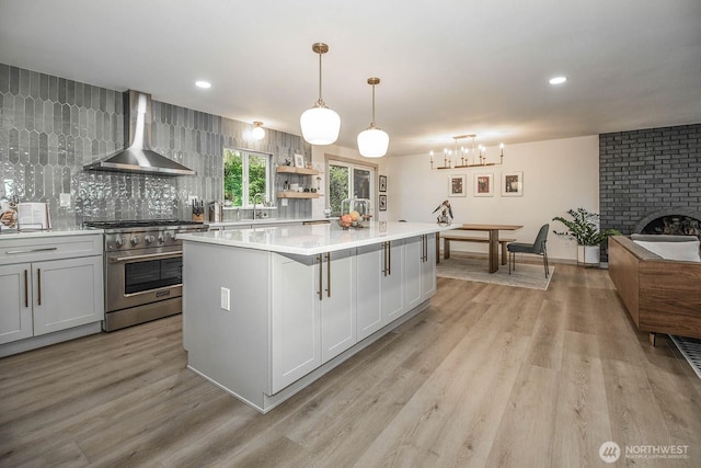 13512 106th Dr SE, Snohomish, WA 98296 - kitchen with wall chimney exhaust hood, high end range, light wood finished floors, a kitchen island, and recessed lighting