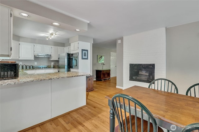 3738 S 189th Pl, Seatac, WA 98188 - kitchen with stainless steel appliances, light wood finished floors, light stone countertops, under cabinet range hood, and white cabinets