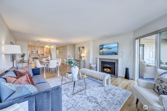524 Maple St Unit 105, Edmonds, WA 98020 - living room featuring a chandelier, crown molding, a warm lit fireplace, and light wood finished floors