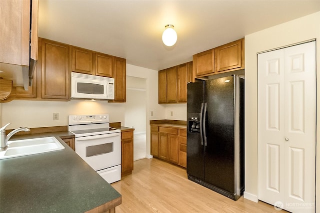 14626 58th Dr SE, Everett, WA 98208 - kitchen featuring white appliances, brown cabinetry, light wood-type flooring, and dark countertops