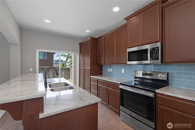 535 Beechwood Ct SW, Olympia, WA 98502 - kitchen with appliances with stainless steel finishes, backsplash, light wood finished floors, an island with sink, and recessed lighting
