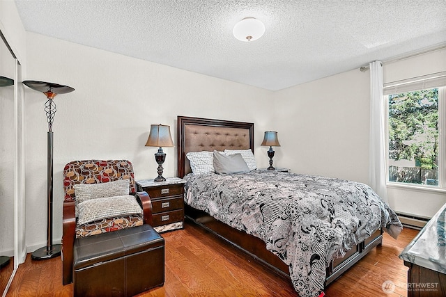 33011 18th Pl S Unit F205, Federal Way, WA 98003 - bedroom featuring wood finished floors, a textured ceiling, and a baseboard radiator