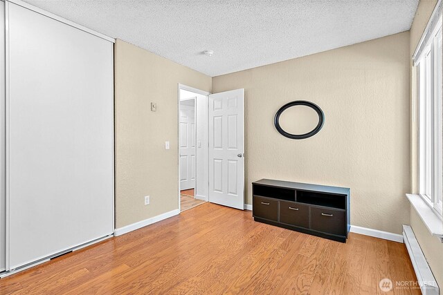 33011 18th Pl S Unit F205, Federal Way, WA 98003 - unfurnished bedroom featuring baseboard heating, a textured ceiling, and wood finished floors