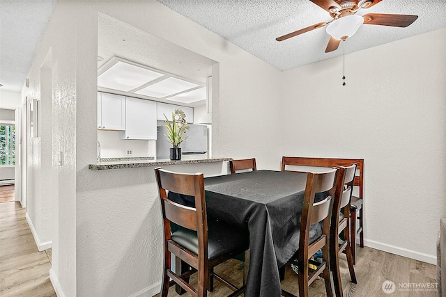 33011 18th Pl S Unit F205, Federal Way, WA 98003 - dining area with light wood-type flooring, a textured ceiling, a textured wall, a ceiling fan, and baseboard heating