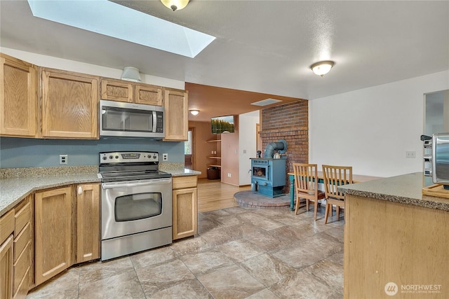 11022 SE 313th St, Auburn, WA 98092 - kitchen featuring stainless steel appliances, a wood stove, a skylight, stone finish floors, and light countertops