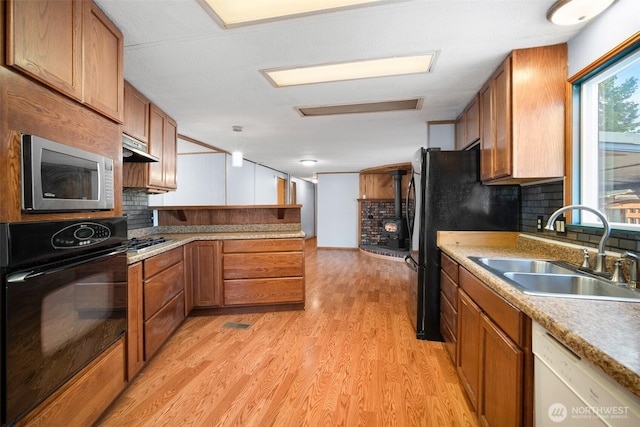 8265 Skeena Way, Blaine, WA 98230 - kitchen with black appliances, brown cabinets, a peninsula, light wood finished floors, and tasteful backsplash