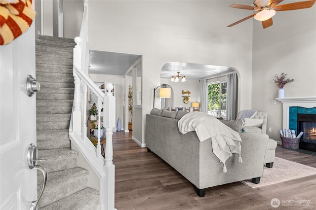 7605 38th Ct SE, Lacey, WA 98503 - living room with arched walkways, a high ceiling, wood finished floors, ceiling fan, and stairs